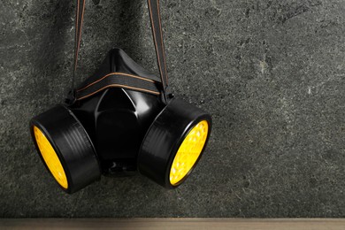 Photo of One respirator mask on gray textured wall, space for text