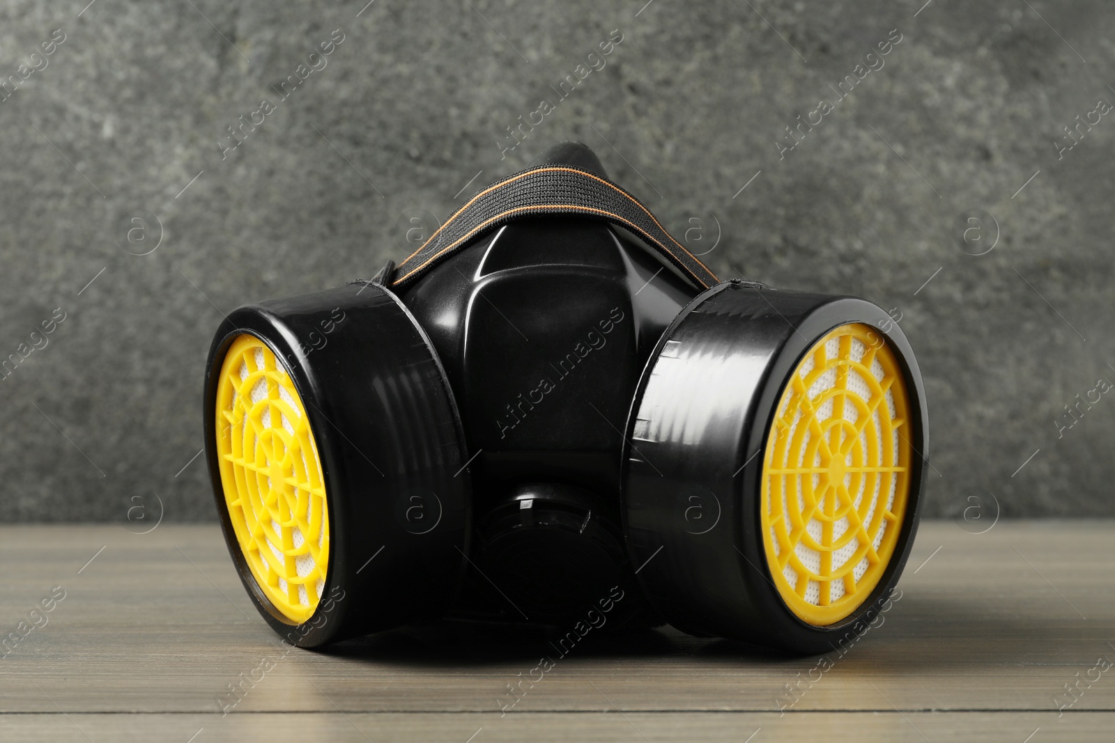 Photo of One respirator mask on wooden table against gray textured wall