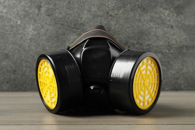 Photo of One respirator mask on wooden table against gray textured wall