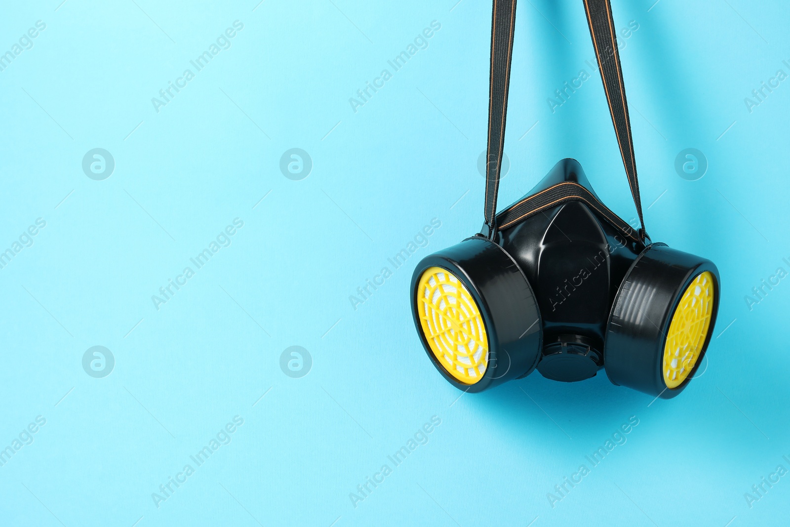 Photo of One respirator mask on light blue background. Space for text