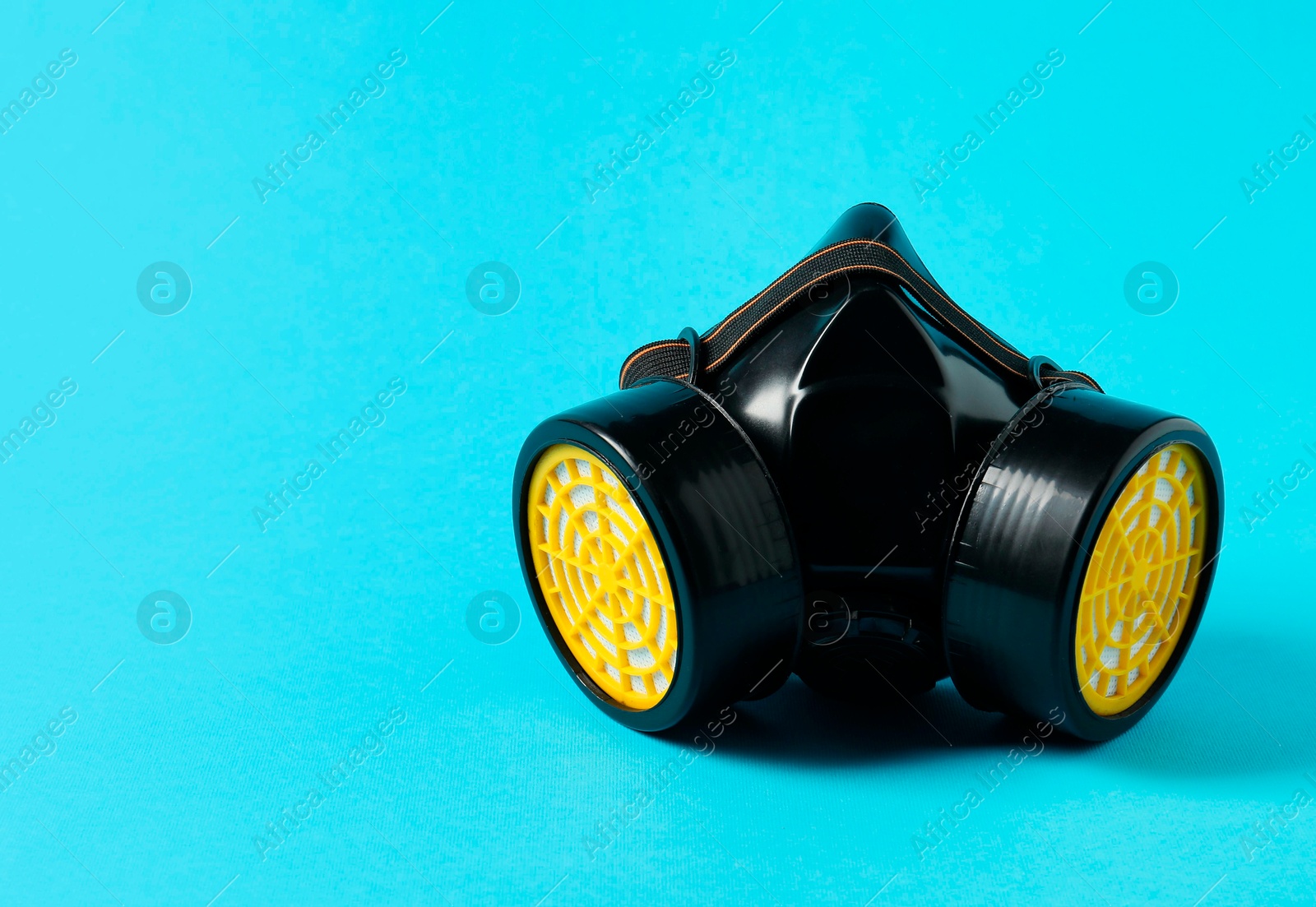 Photo of One respirator mask on light blue background, space for text