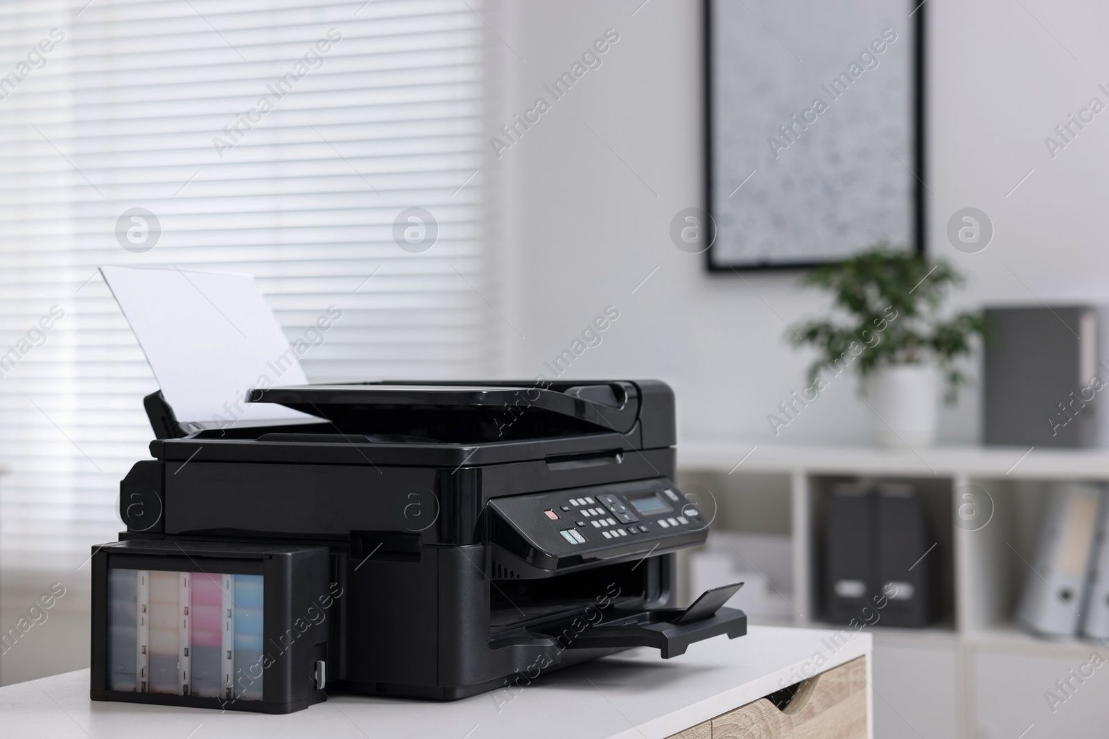 Photo of Modern printer with paper on table in office. Space for text