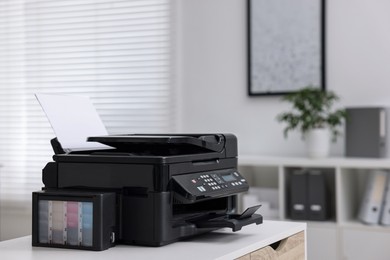 Modern printer with paper on table in office. Space for text