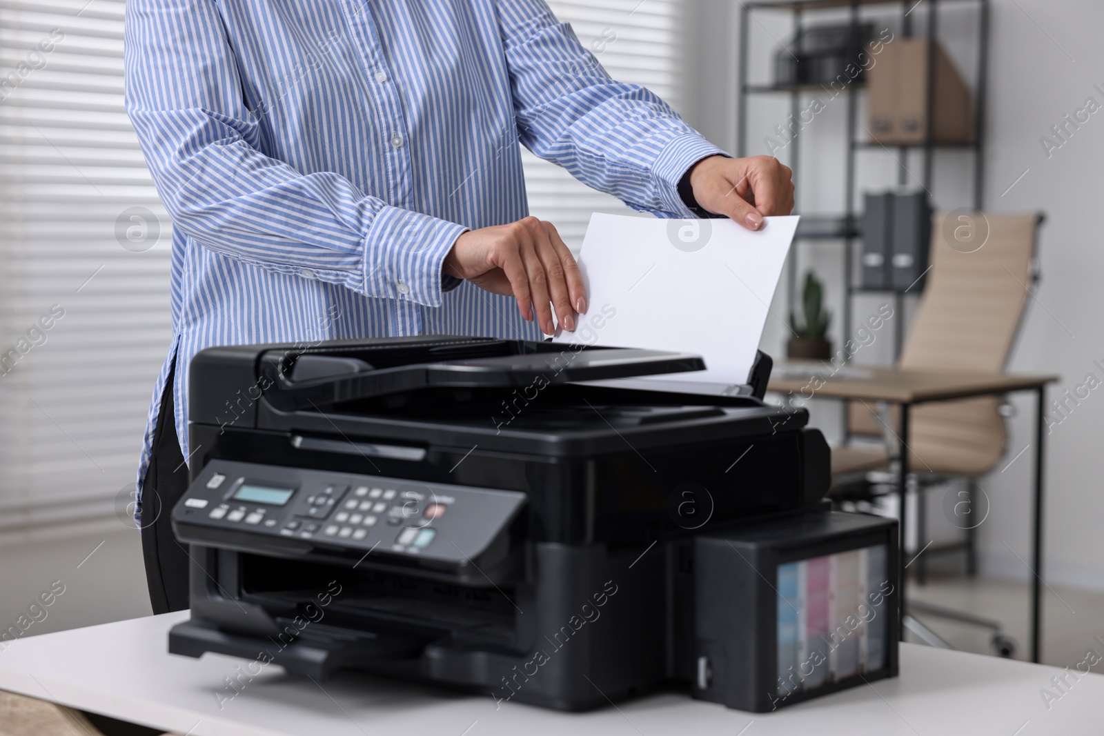 Photo of Woman using modern printer at workplace indoors, closeup