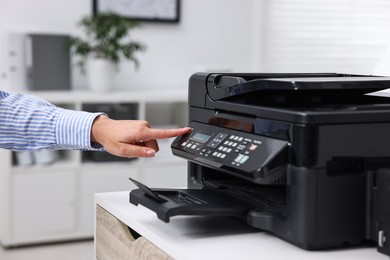 Photo of Woman using modern printer at workplace indoors, closeup