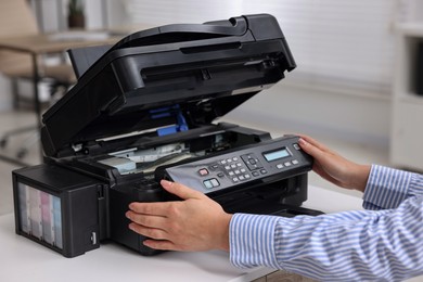 Woman using modern printer at workplace indoors, closeup