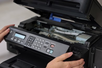 Photo of Woman using modern printer at workplace indoors, closeup