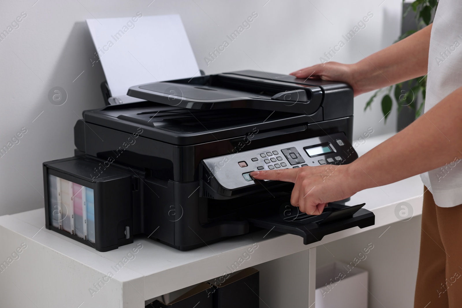 Photo of Woman using modern printer at workplace indoors, closeup