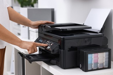 Photo of Woman using modern printer at workplace indoors, closeup