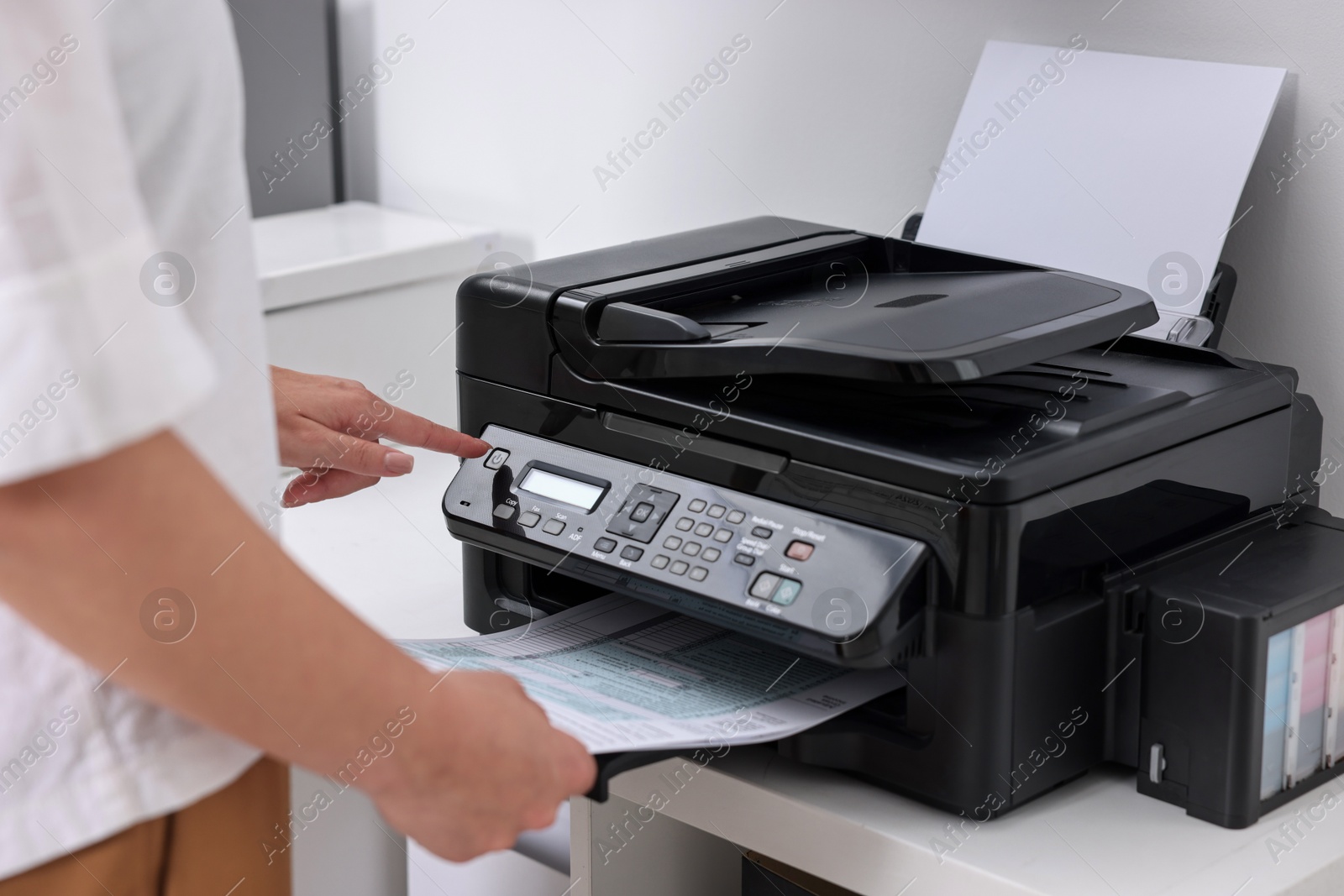 Photo of Woman using modern printer at workplace indoors, closeup