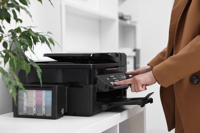 Photo of Woman using modern printer at workplace indoors, closeup