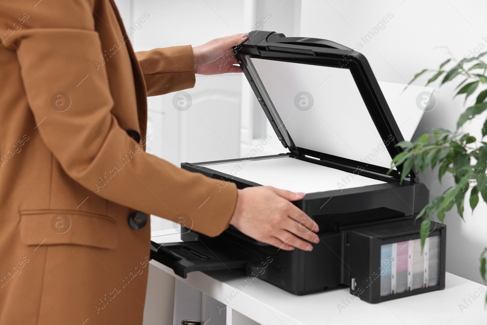 Photo of Woman using modern printer at workplace indoors, closeup