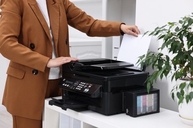 Photo of Woman using modern printer at workplace indoors, closeup