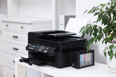 Modern printer with paper on table in office