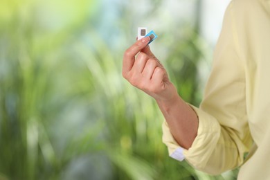 Photo of Woman with SIM cards against blurred green background, closeup. Space for text