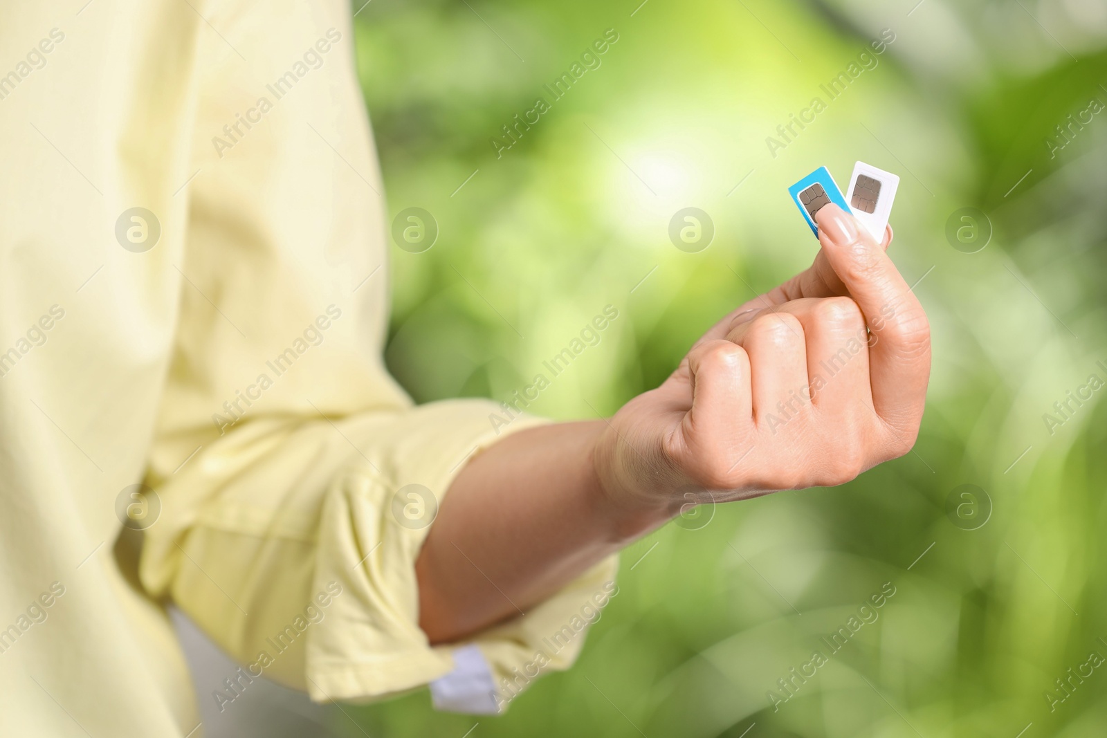 Photo of Woman with SIM cards against blurred green background, closeup