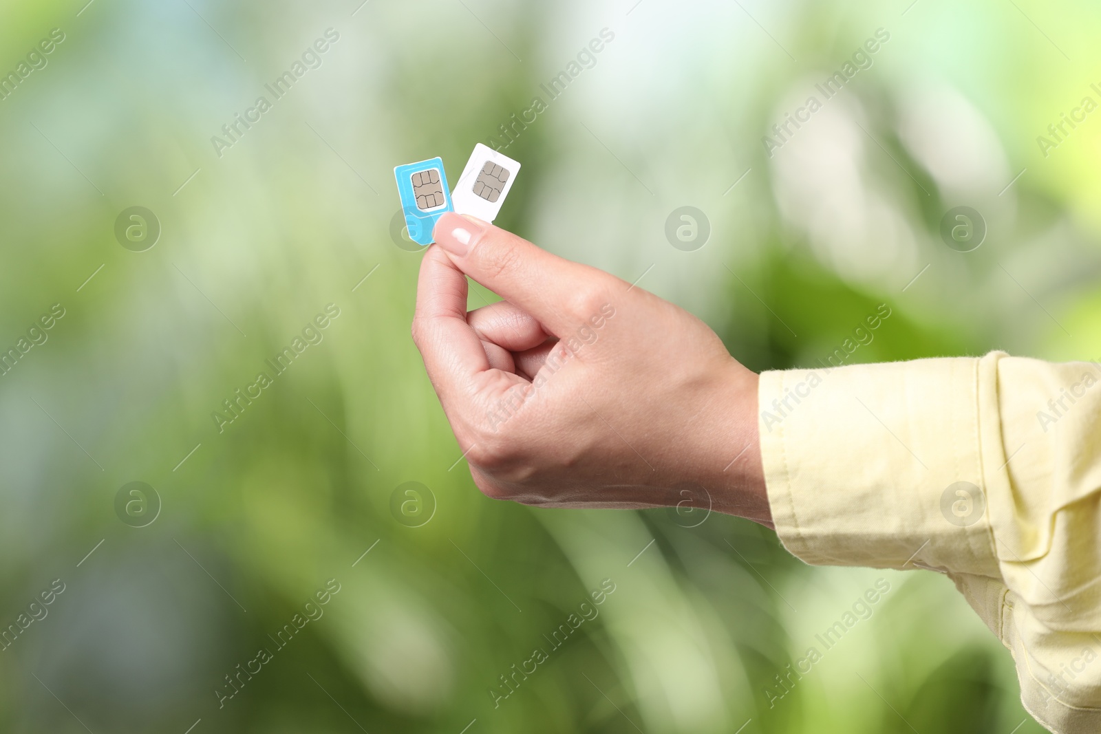 Photo of Woman with SIM cards against blurred green background, closeup