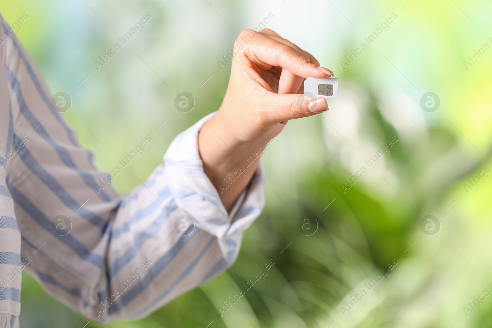 Photo of Woman with SIM card against blurred green background, closeup