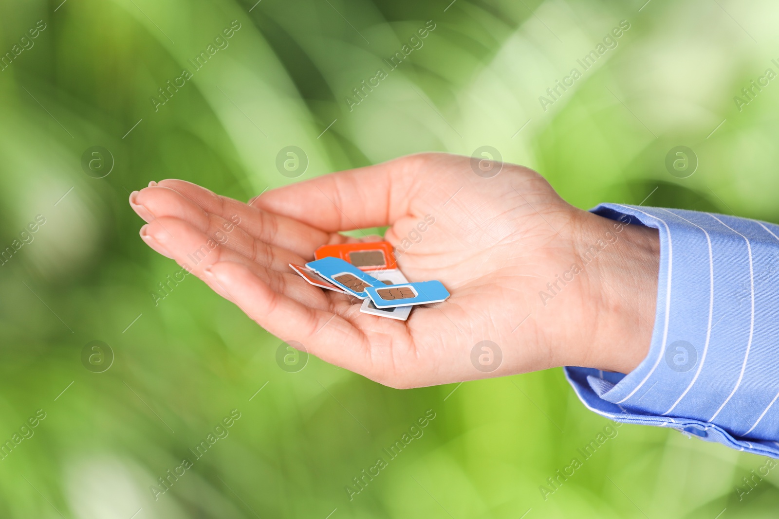 Photo of Woman with SIM cards against blurred green background, closeup