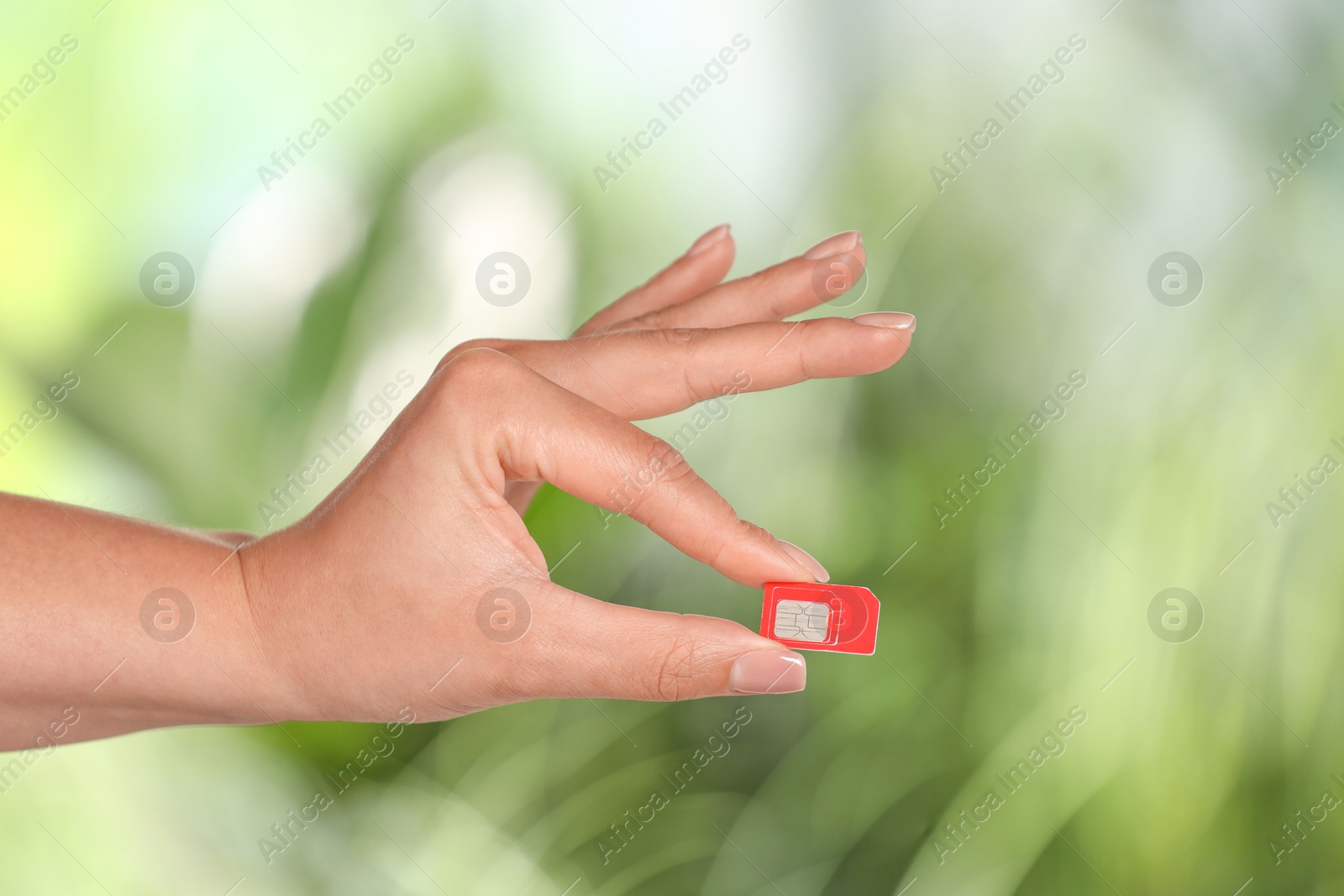 Photo of Woman with SIM card against blurred green background, closeup