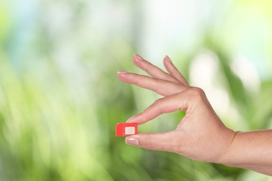 Photo of Woman with SIM card against blurred green background, closeup, Space for text