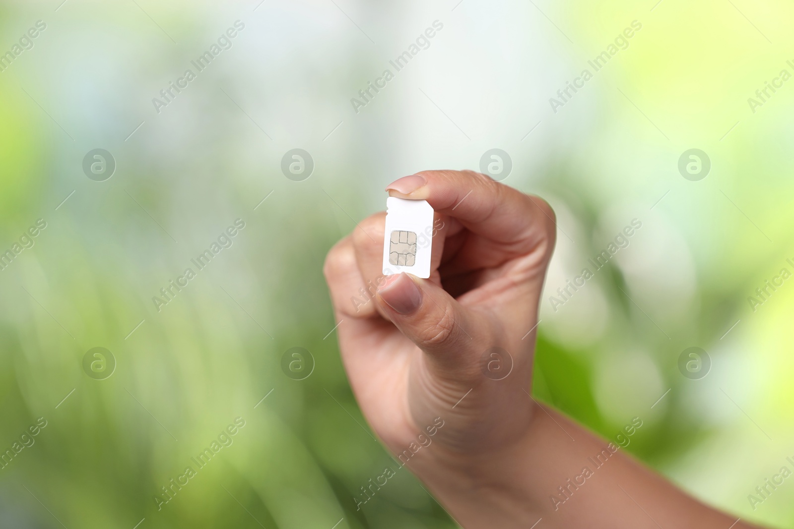 Photo of Woman with SIM card against blurred green background, closeup