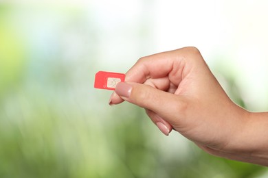 Photo of Woman with SIM card against blurred green background, closeup