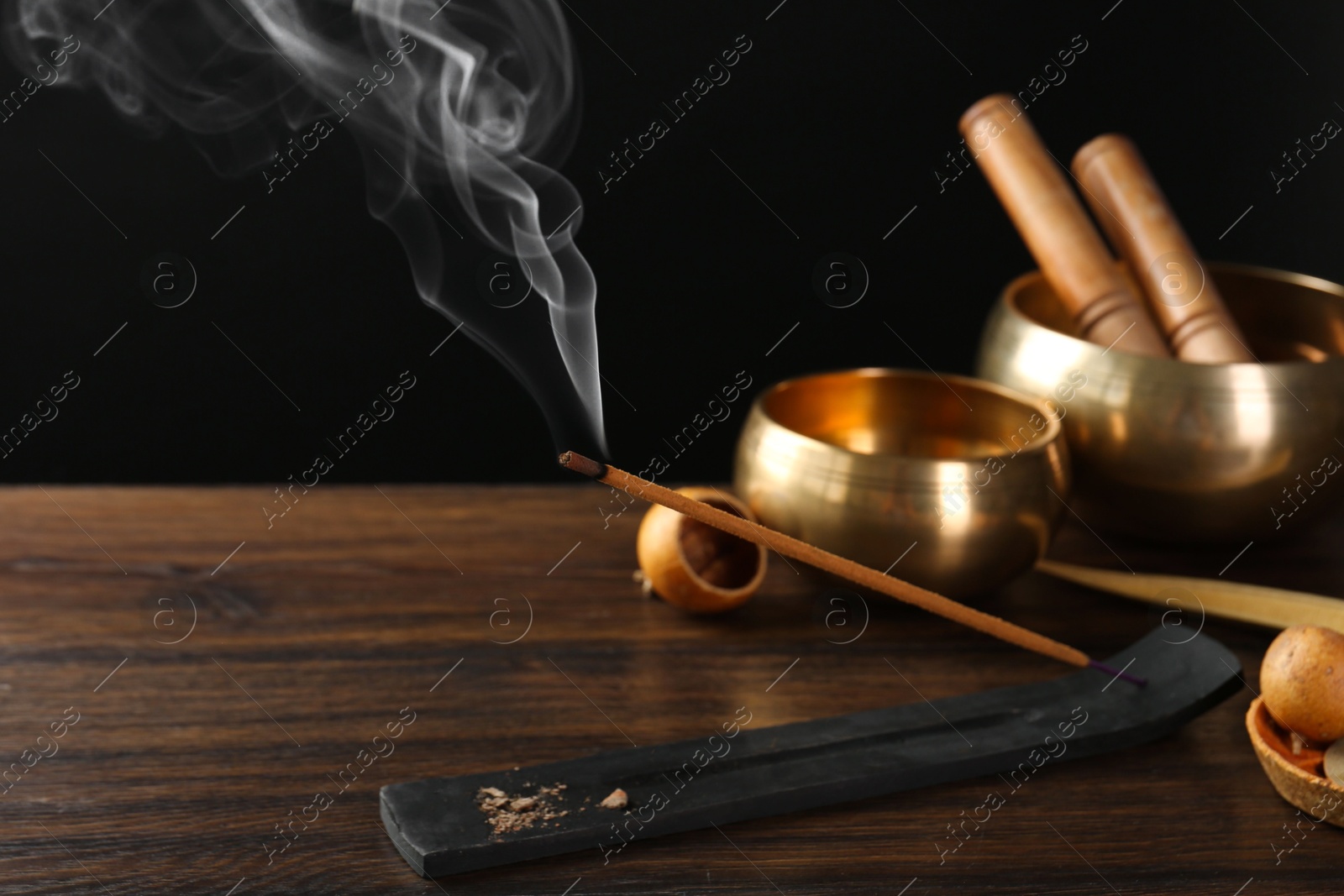 Photo of Aromatic incense stick smoldering in holder with Om signs on wooden table