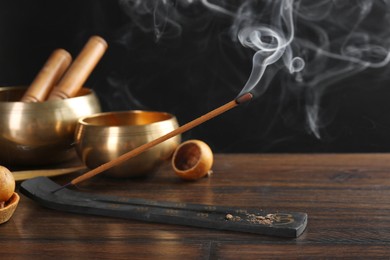 Photo of Aromatic incense stick smoldering in holder with Om signs on wooden table