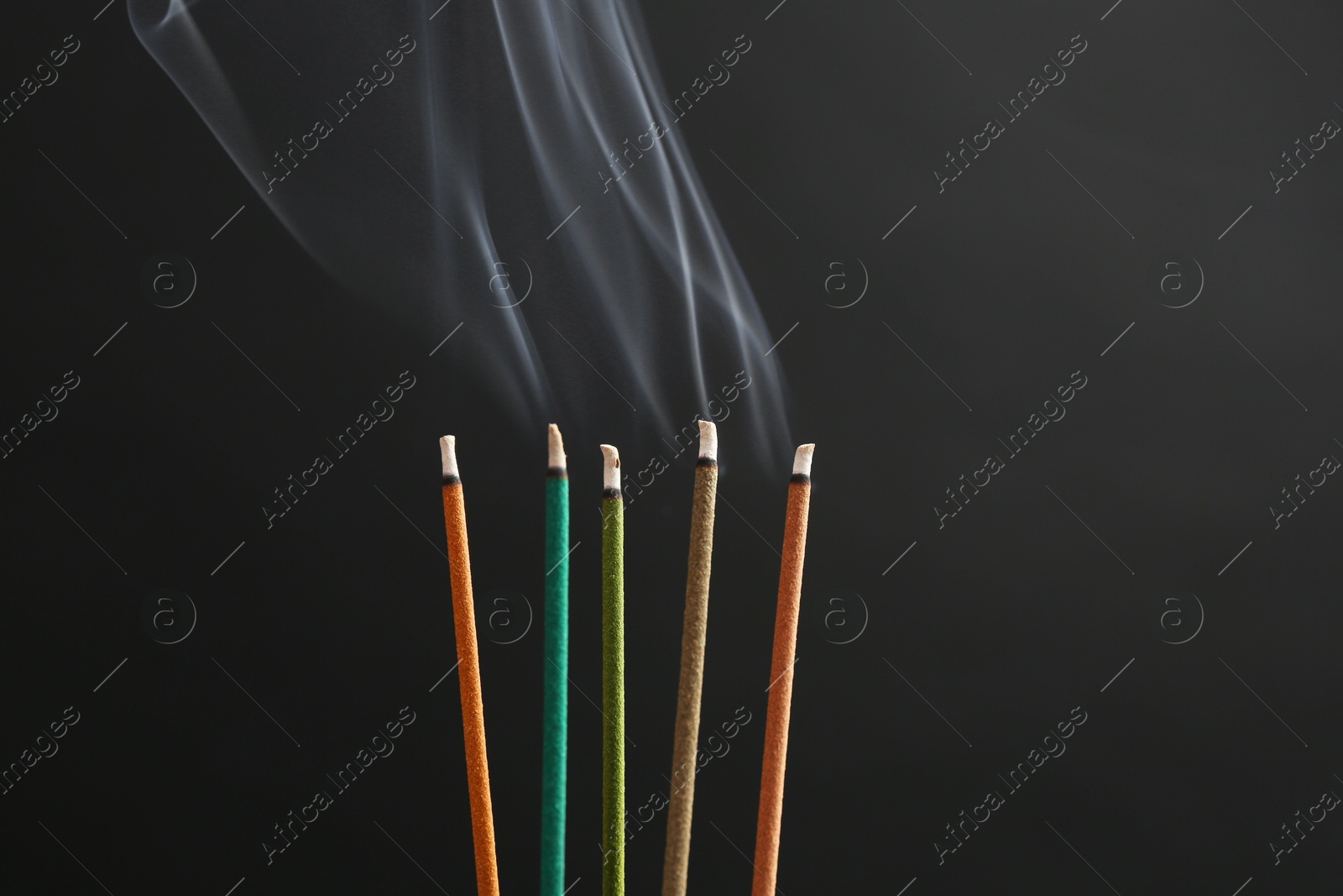 Photo of Aromatic incense sticks smoldering on black background