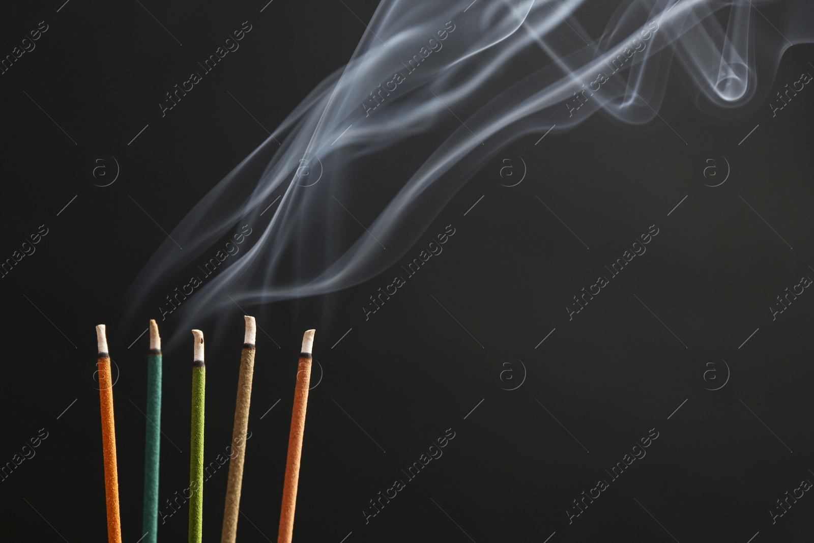 Photo of Aromatic incense sticks smoldering on black background