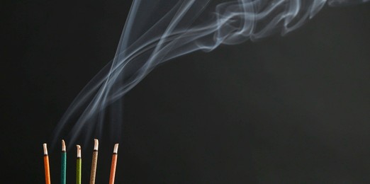 Photo of Aromatic incense sticks smoldering on black background, space for text. Banner design