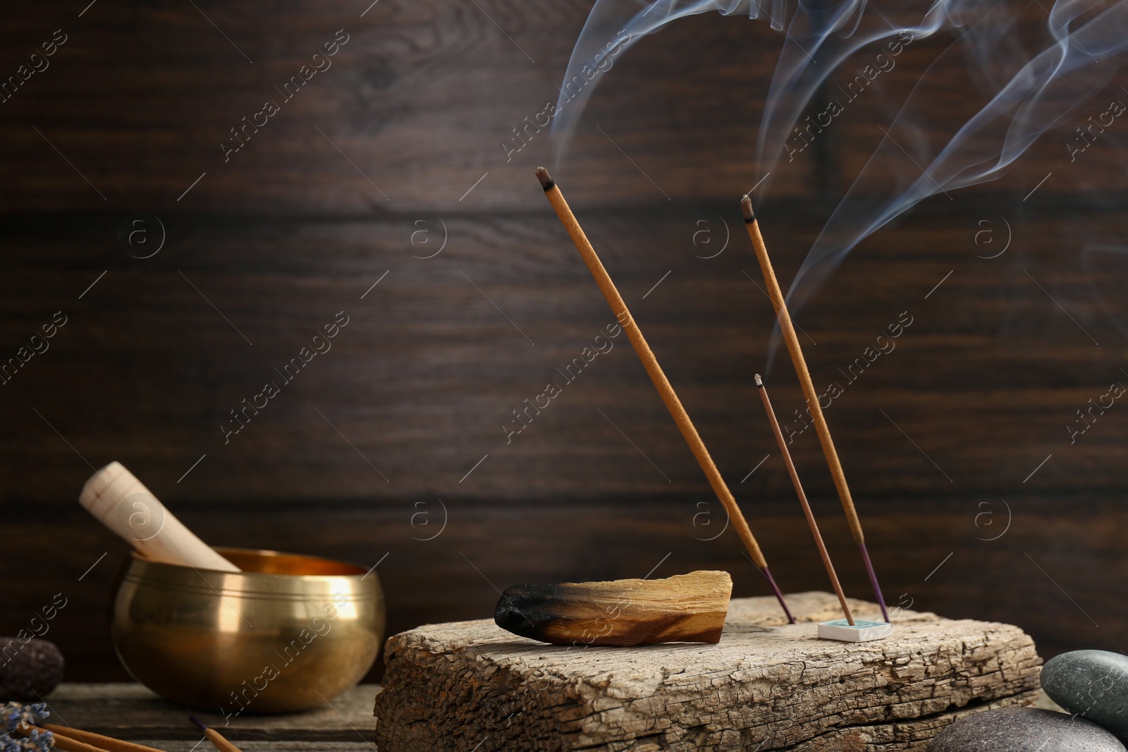 Photo of Aromatic incense sticks smoldering on wooden table