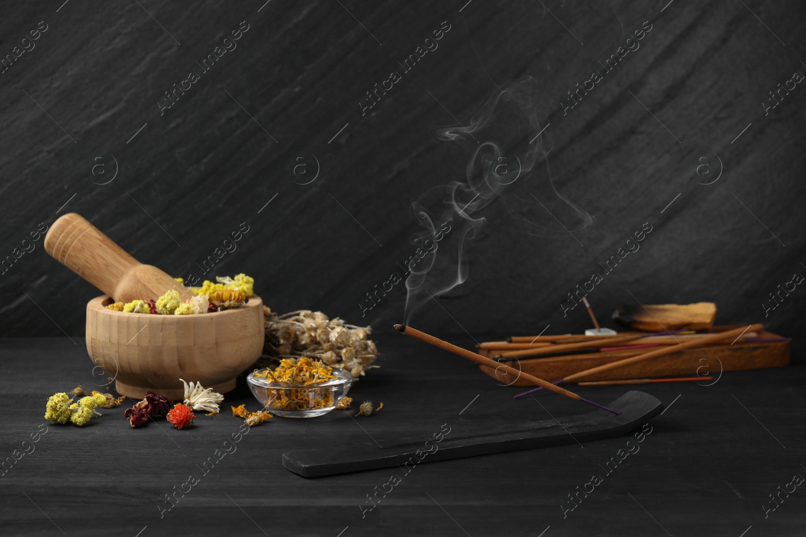 Photo of Aromatic incense stick smoldering in holder with om sign on black table