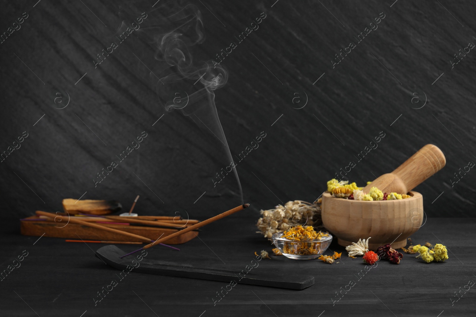 Photo of Aromatic incense stick smoldering in holder with om sign on black table. Space for text