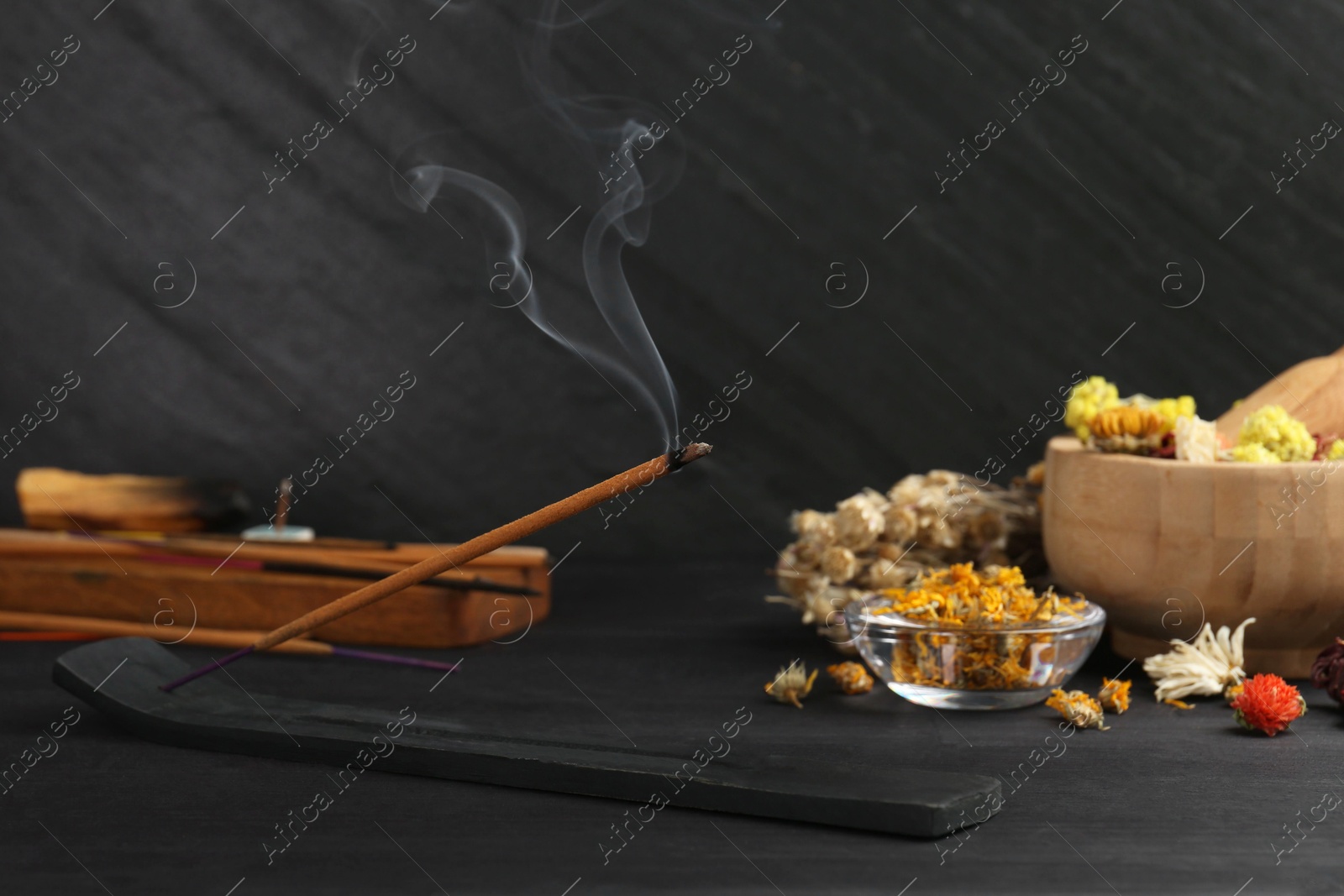 Photo of Aromatic incense stick smoldering in holder with om sign on black table. Space for text