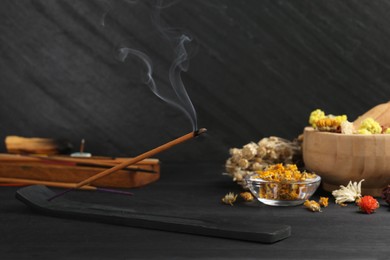 Aromatic incense stick smoldering in holder with om sign on black table. Space for text