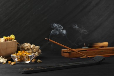 Photo of Aromatic incense stick smoldering in holder with om sign on black table. Space for text