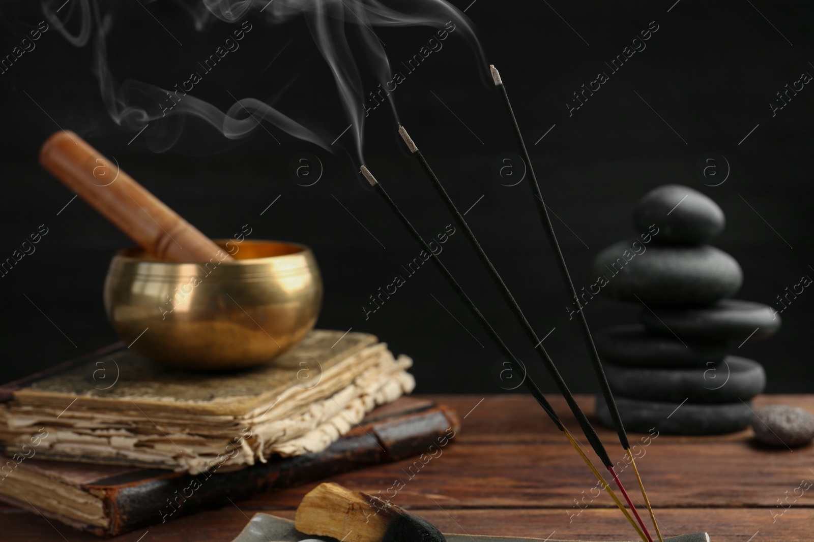 Photo of Aromatic incense sticks smoldering on wooden table