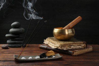 Photo of Aromatic incense sticks smoldering on wooden table