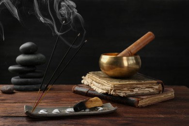 Photo of Aromatic incense sticks smoldering on wooden table