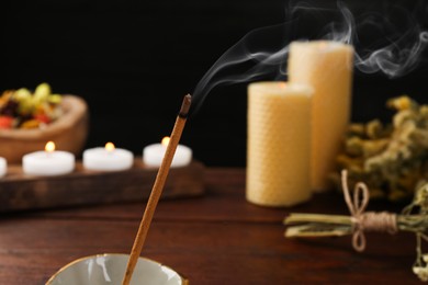 Aromatic incense stick smoldering on blurred background