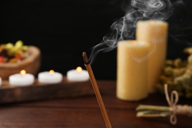 Photo of Aromatic incense stick smoldering on blurred background, closeup