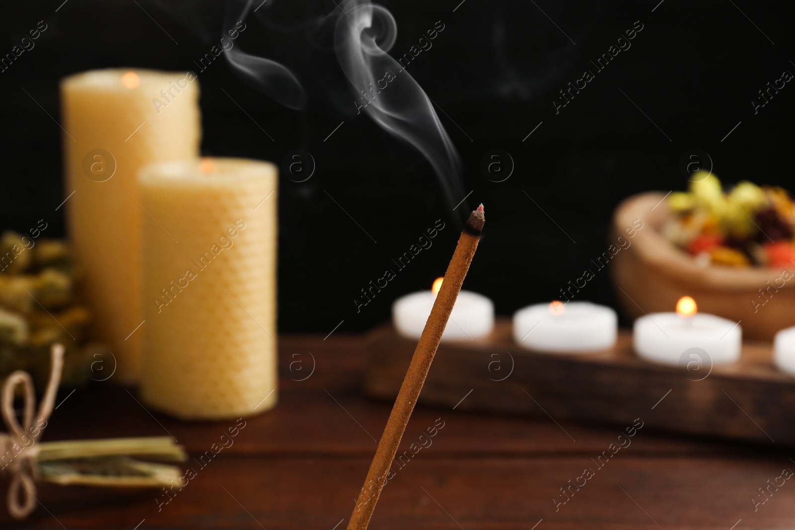 Photo of Aromatic incense stick smoldering on blurred background, closeup