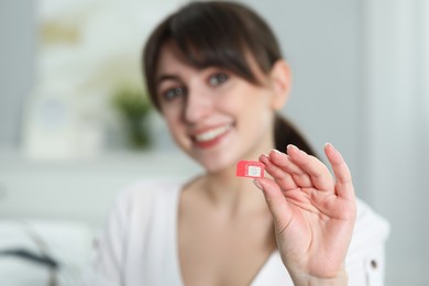 Photo of Woman holding SIM card at home, selective focus