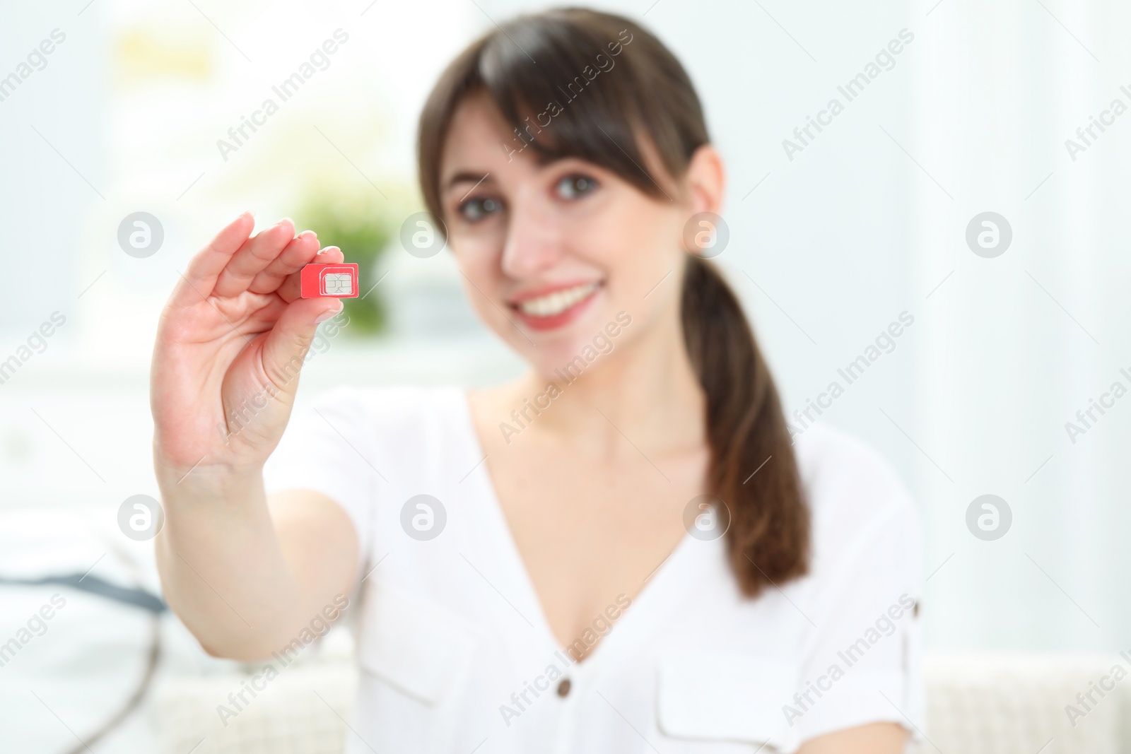 Photo of Woman holding SIM card at home, selective focus