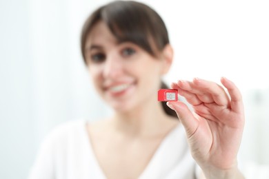 Photo of Woman holding SIM card at home, selective focus