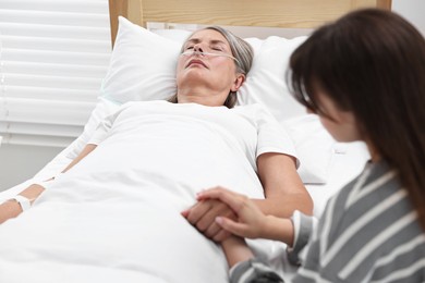 Coma patient. Woman near her unconscious mother in hospital