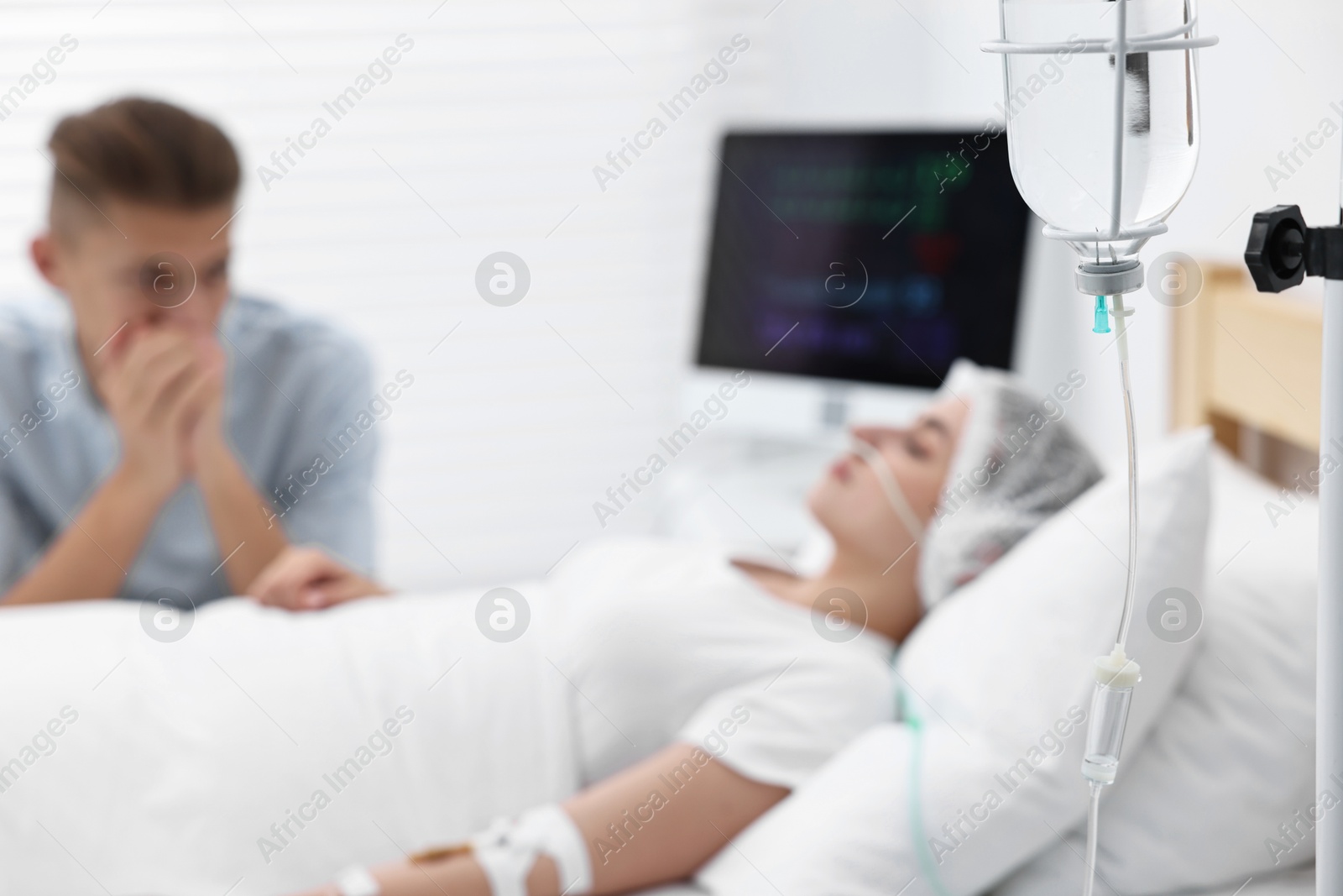 Photo of Coma patient. Sad young man near his unconscious wife in hospital, selective focus