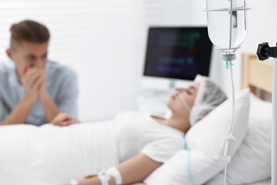 Photo of Coma patient. Sad young man near his unconscious wife in hospital, selective focus